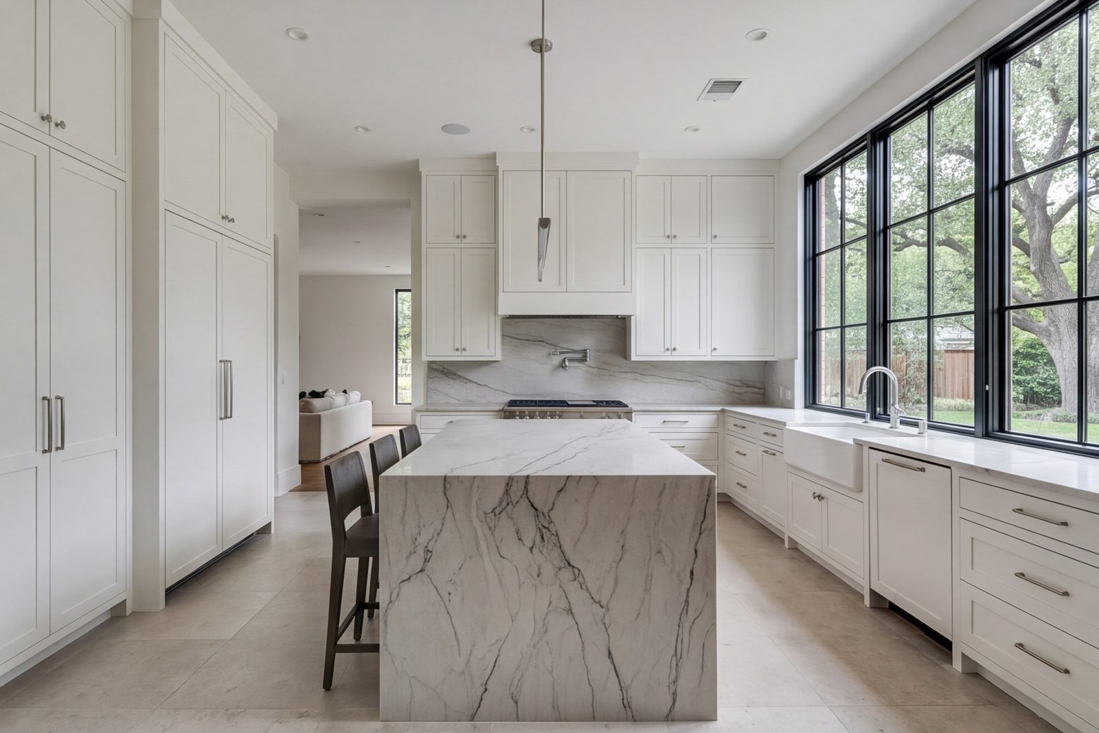 Turtle Creek kitchen with ceiling-height cabinets, stone island and tall windows along one wall